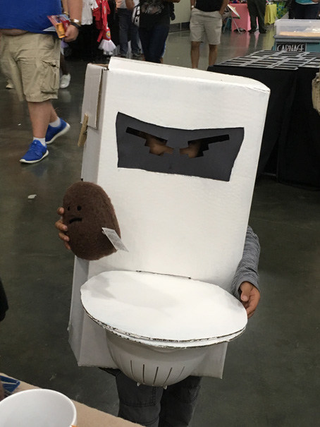 Kid dressed as a toilet holding a poop